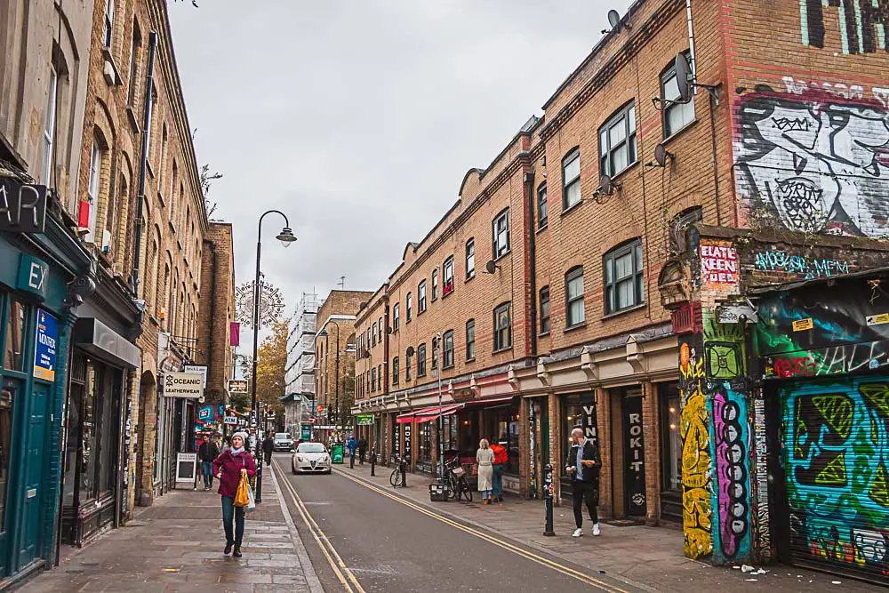 Brick Lane in London mit Street Art, Häusern und Restaurants